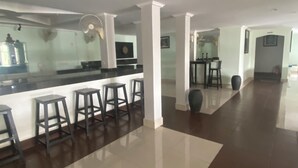 Una cocina moderna y espaciosa con barra, columnas blancas y piso de baldosas.