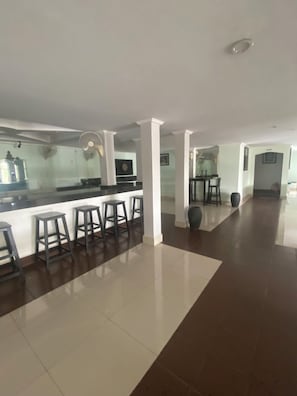 Una cocina moderna y espaciosa con barra, columnas blancas y piso de baldosas.