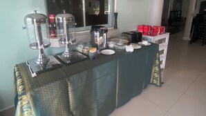 Disposición de un bufé con un reloj, recipientes de comida y una ventana al fondo.