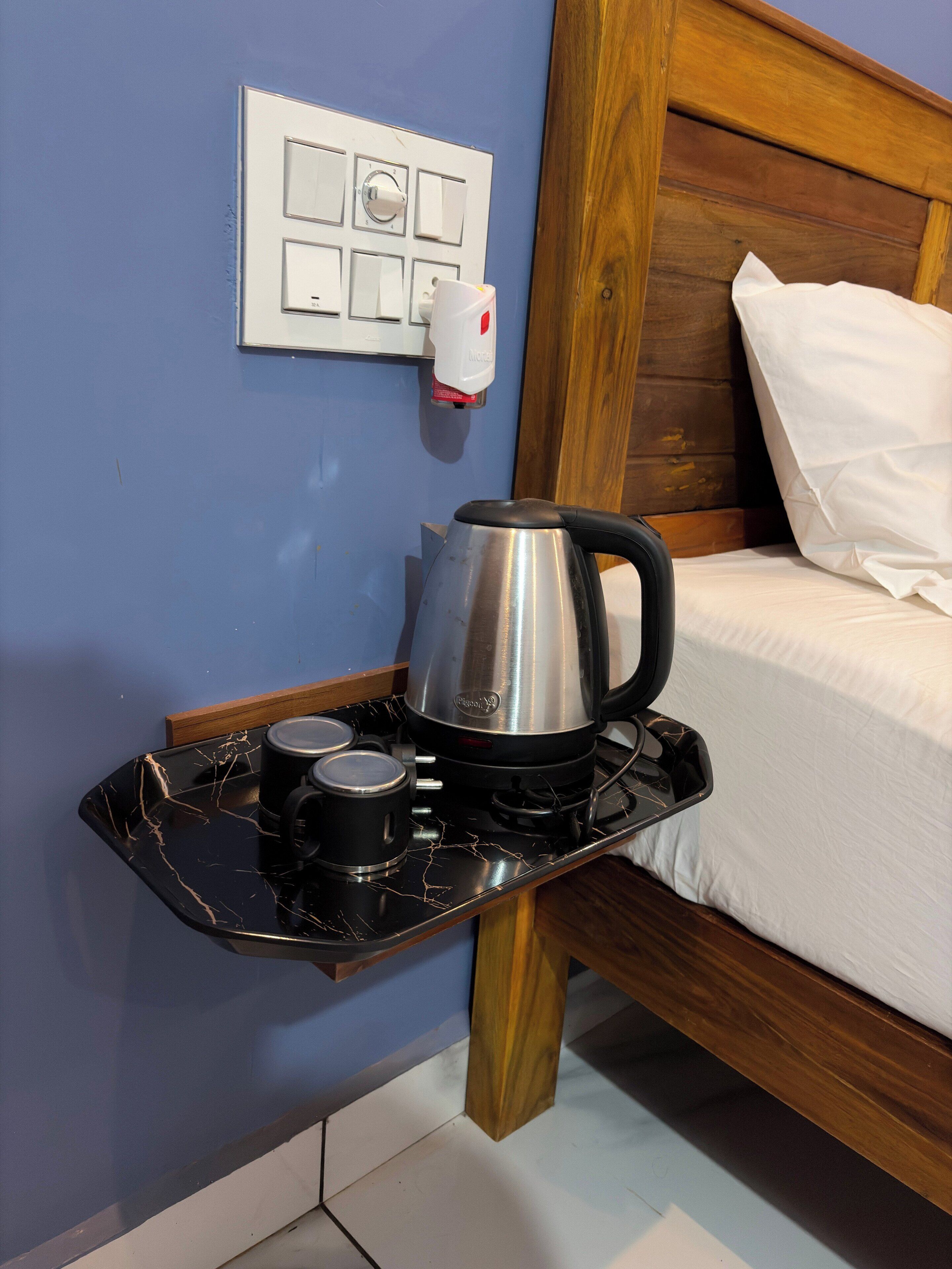 A kitchen area with a kettle, a coffee maker, and a tray.