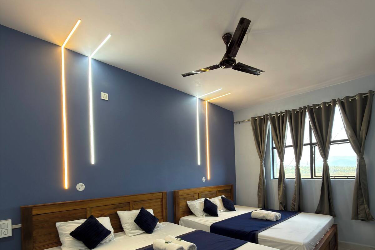 A hotel room with two beds, wooden headboards, and a ceiling fan.