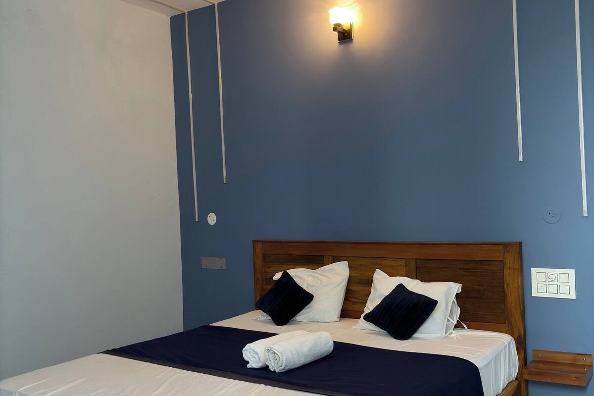 A neatly made bed with a wooden headboard, a ceiling fan, and a wall-mounted light fixture.