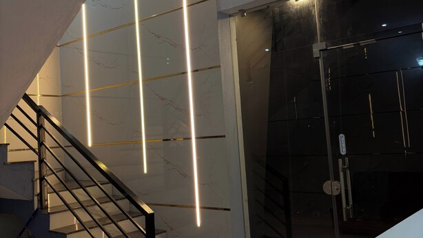 A modern staircase with glass railings and illuminated lines, leading to a dark room with a door marked "pull". - Arna Inn Luxury Stay (Bhatkal)