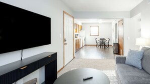 A modern living room with a flat-screen TV, a round coffee table, and a grey sofa. - Near K-State Campus - Central Manhattan Stay (Manhattan)