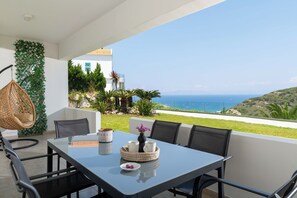 Une terrasse avec une table dressée pour quatre personnes, offrant une vue sur la côte.