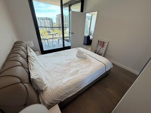 A modern bedroom with a large bed, a sofa, and a balcony with a view of buildings. - Bright 2-bedroom apartment in pleasant Zetland with AC (Zetland)
