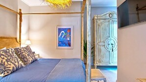 A four-poster bed with a blue and white striped bedspread, a leopard print pillow, and a framed abstract painting on the wall. - Indigo Apartment by Corfuescapes  (Corfu)