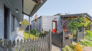 Una zona residencial con una casa gris, una puerta roja y una valla de madera.