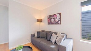 Ein modernes Wohnzimmer mit einem grauen Sofa, einer Stehlampe und einem floralen Gemälde an der Wand.