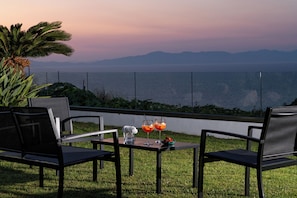 A terrace with two chairs and a table, a bowl of fruit, and two glasses of orange juice. - Island Hills- Sunshine, Apartment (Rhodes)