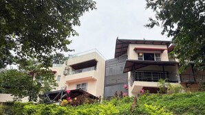 A modern multi-story residential building with balconies and a garden area. -  Lords Riverside Resort Muduba - A Wellness Nature Retreat (Tirthalli)