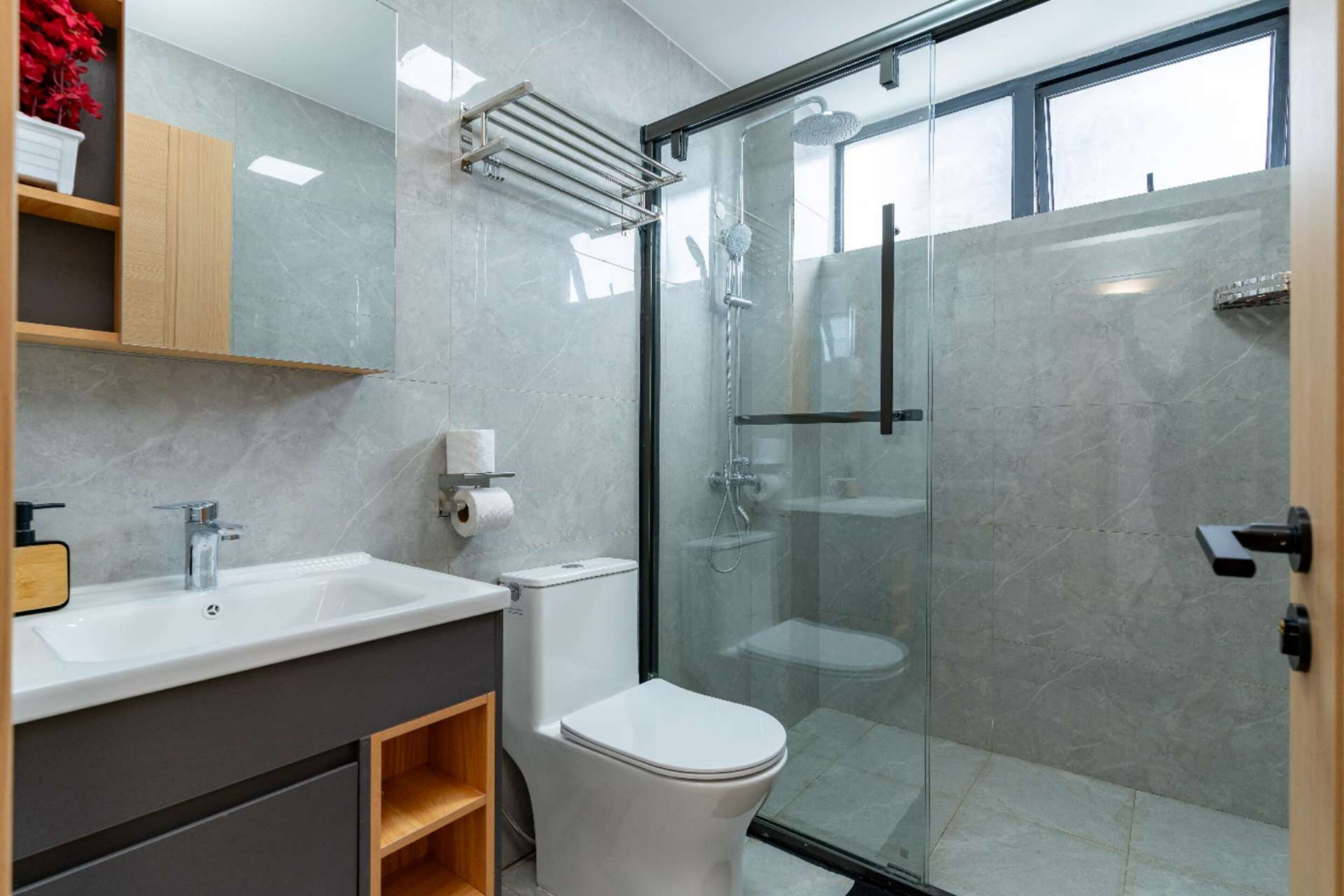 Une salle de bain moderne avec une douche à parois de verre, un lavabo blanc et des toilettes.
