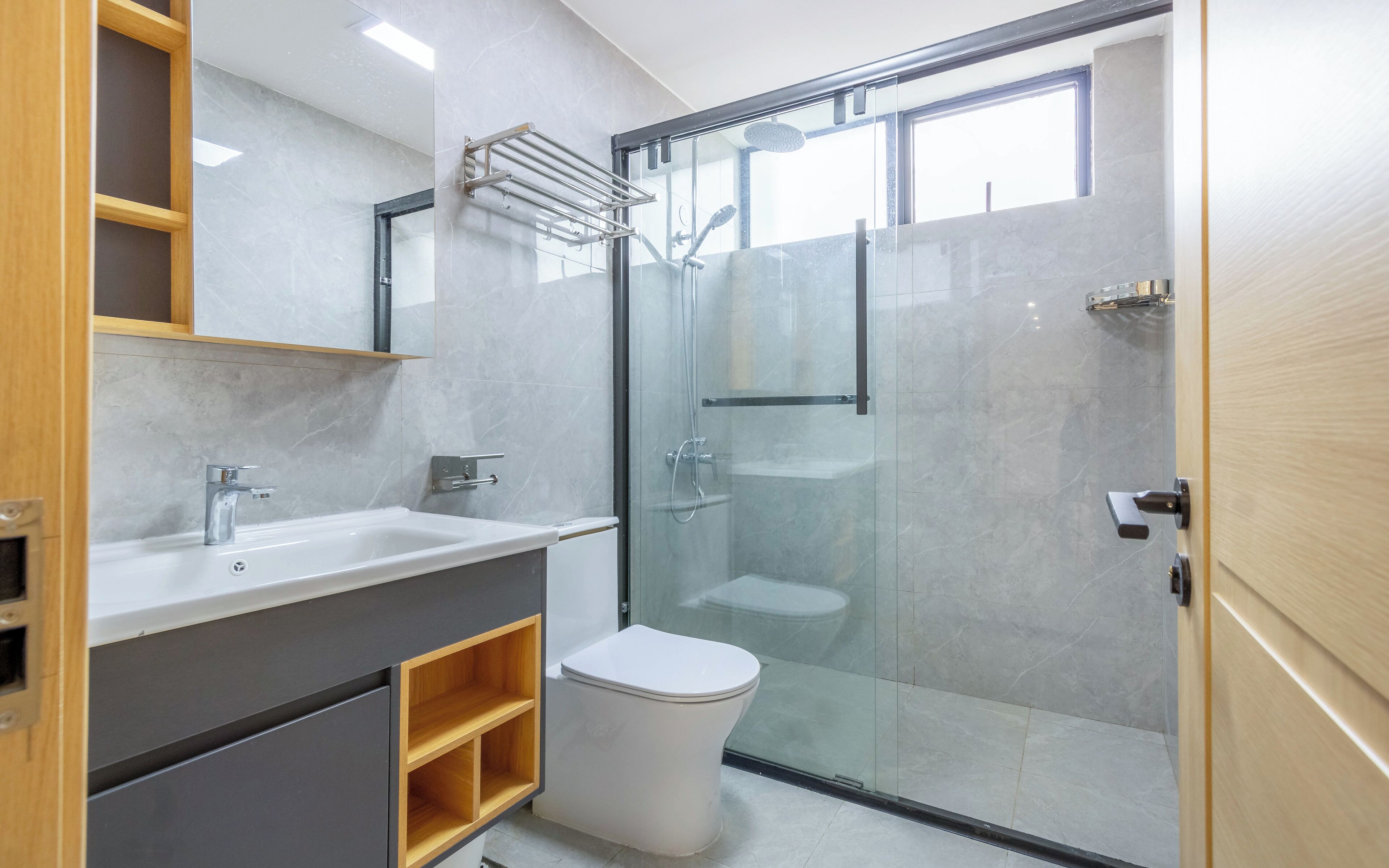 Un baño moderno con ducha acristalada, lavabo blanco y retrete.