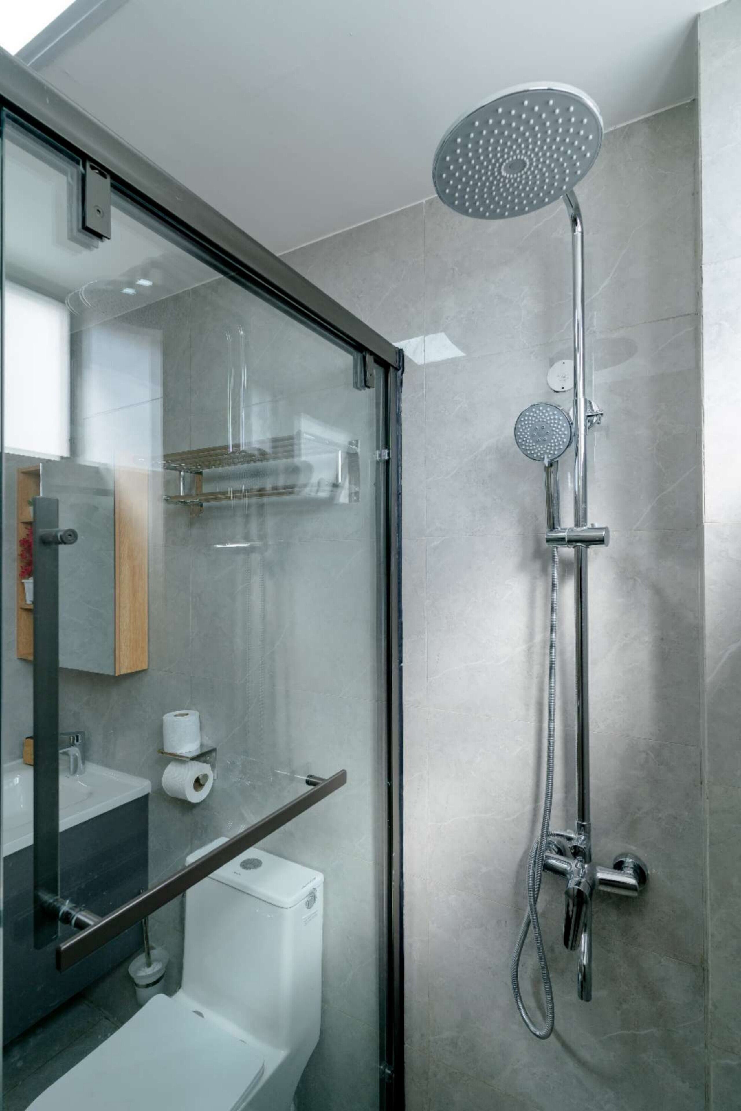 A modern bathroom with a glass-enclosed shower, a toilet, and a sink.