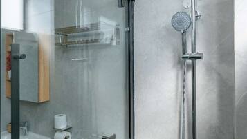 A modern bathroom with a glass-enclosed shower, a toilet, and a sink.