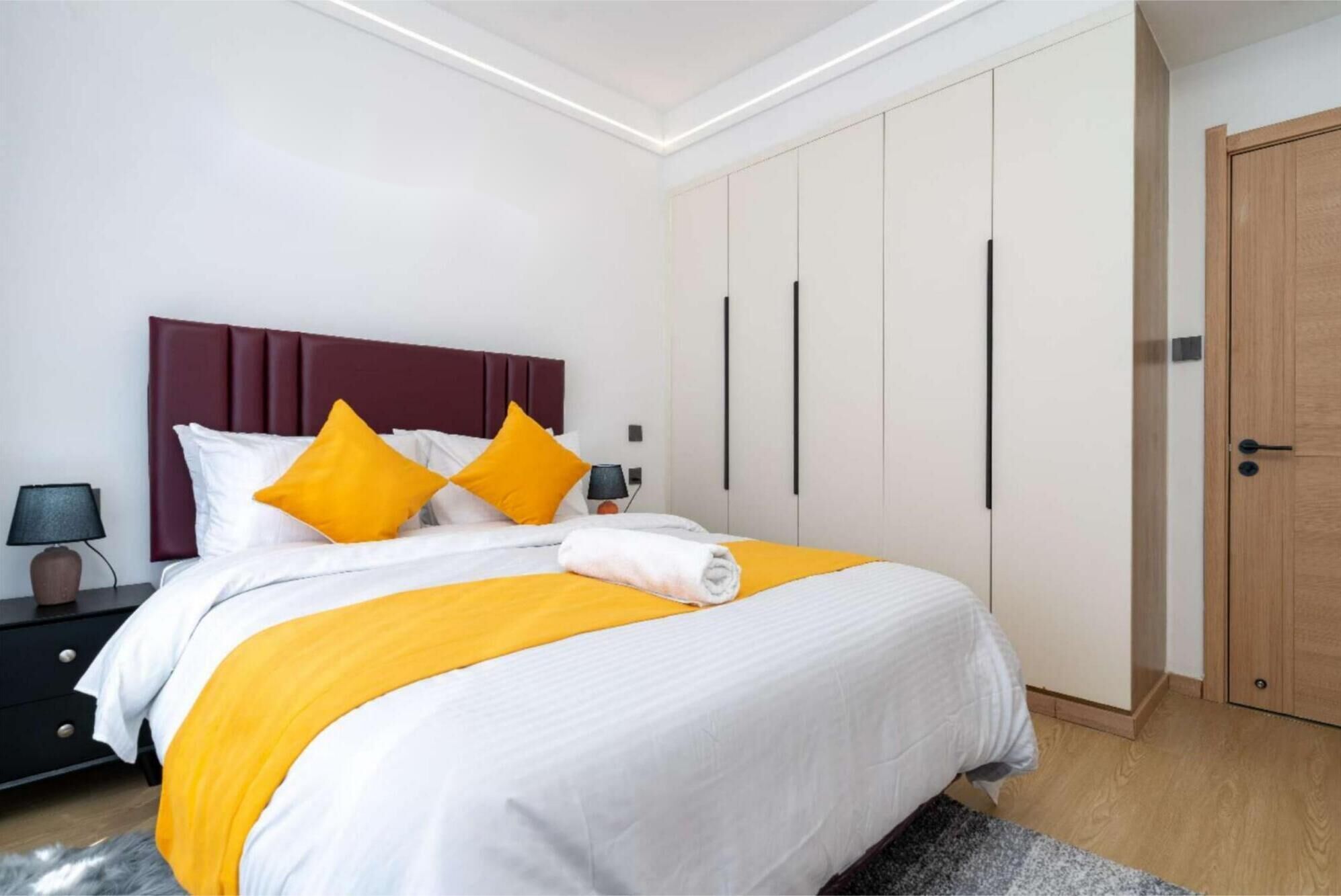 A modern bedroom with a bed, nightstands, and a wardrobe.
