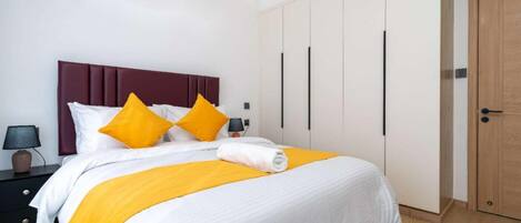 A modern bedroom with a bed, nightstands, and a wardrobe.