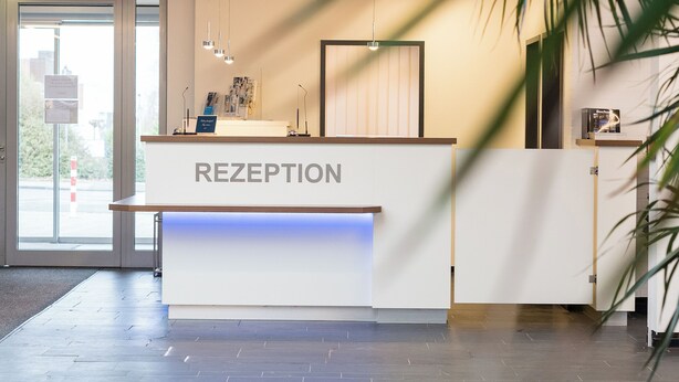 Balcão de recepção com uma placa que diz "RECEPTION" em um edifício moderno.
