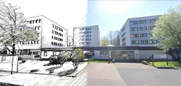 Un bâtiment moderne à plusieurs étages, doté de grandes fenêtres et d’un espace d’entrée pavé avec un chemin.