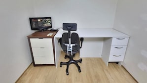Un petit bureau privé, équipé d’un bureau, d’une chaise et d’un écran d’ordinateur.