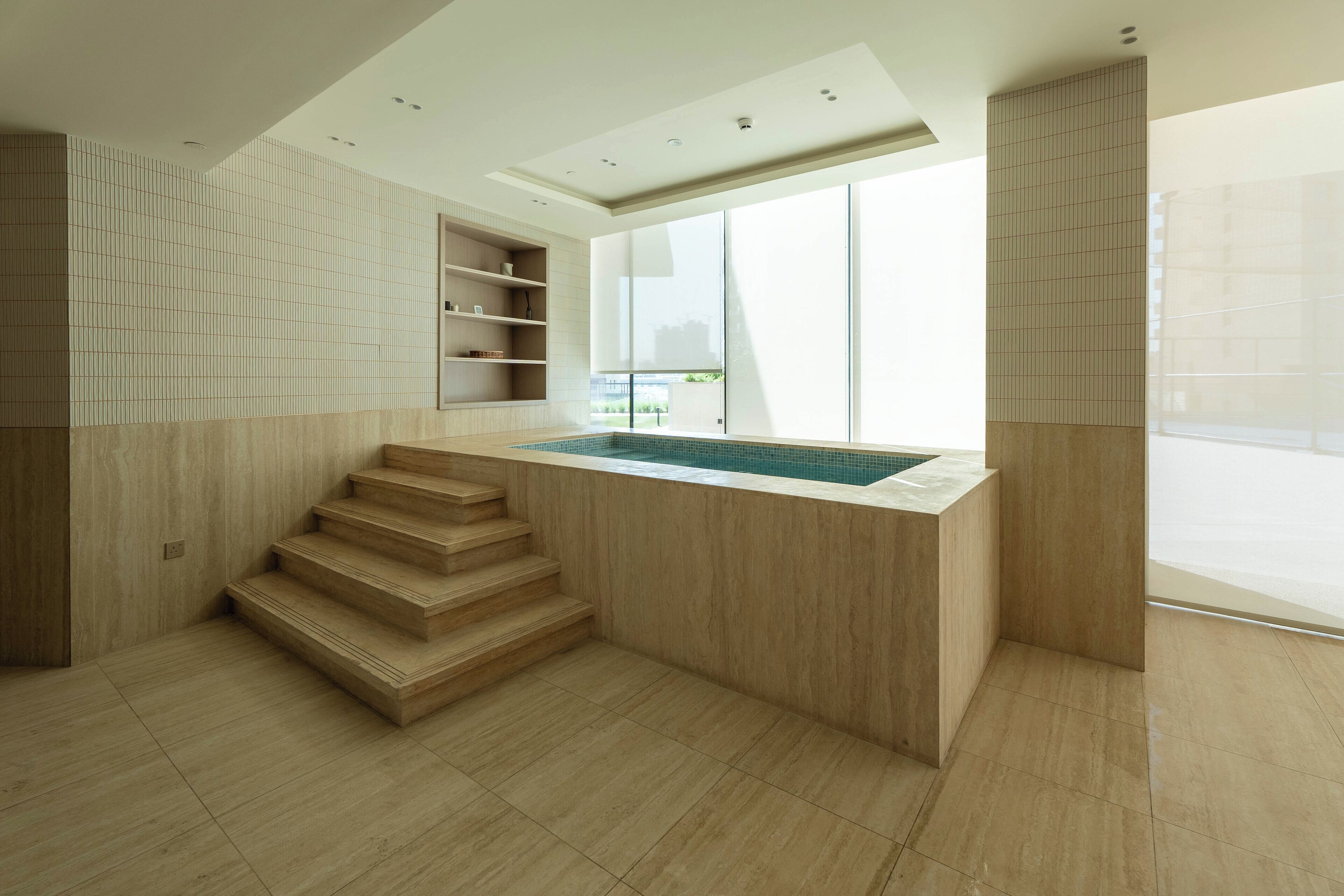 Een modern interieur met een ingebouwd zwembad, houten trappen en grote ramen.