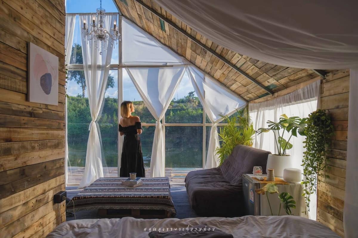 Una habitación con un ventanal grande, una cama, un sofá y una araña.