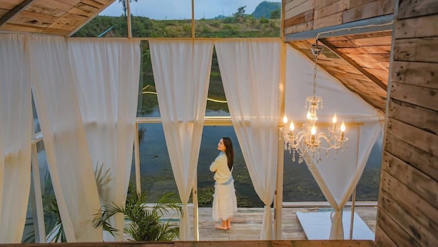 A wooden cabin with large windows, white curtains, and a chandelier. - Nubdao Glamping (Kanchanaburi)