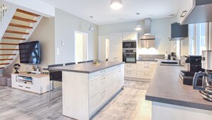 Una cocina moderna con una isla central, electrodomésticos integrados y un comedor con televisor.