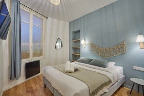 A bedroom with a bed, a window with curtains, a wall-mounted macrame piece, and a bedside table. - Apartment in the center of Paris-Sacre Coeur (Paris)