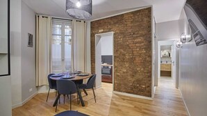 Un espace repas moderne avec un mur d’accent en briques, un plancher en bois et une table à manger pour quatre personnes.