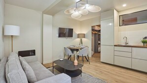 En moderne stue med sofa, sofabord og spiseområde med stole og en lampe.