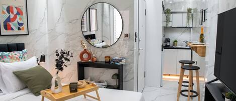 A modern bedroom with a bed, bedside table, and a mirror.