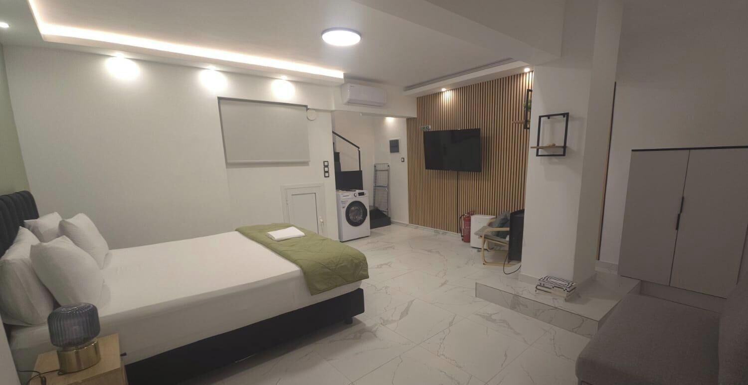 Ein modernes Hotelzimmer mit Bett, Waschmaschine, Fernseher und Kleiderschrank.