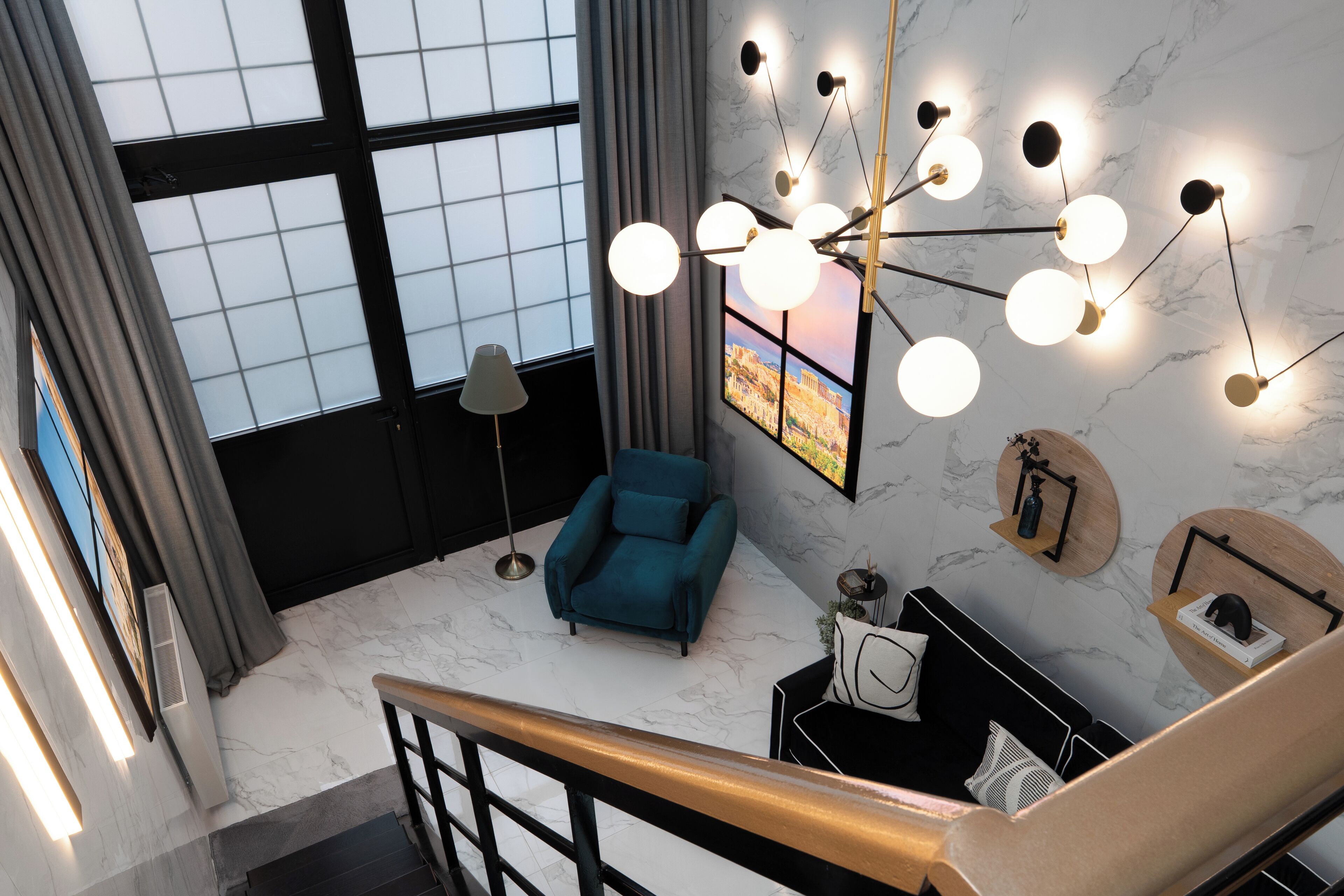 A modern living room with a blue armchair, a black sofa, and a unique chandelier.