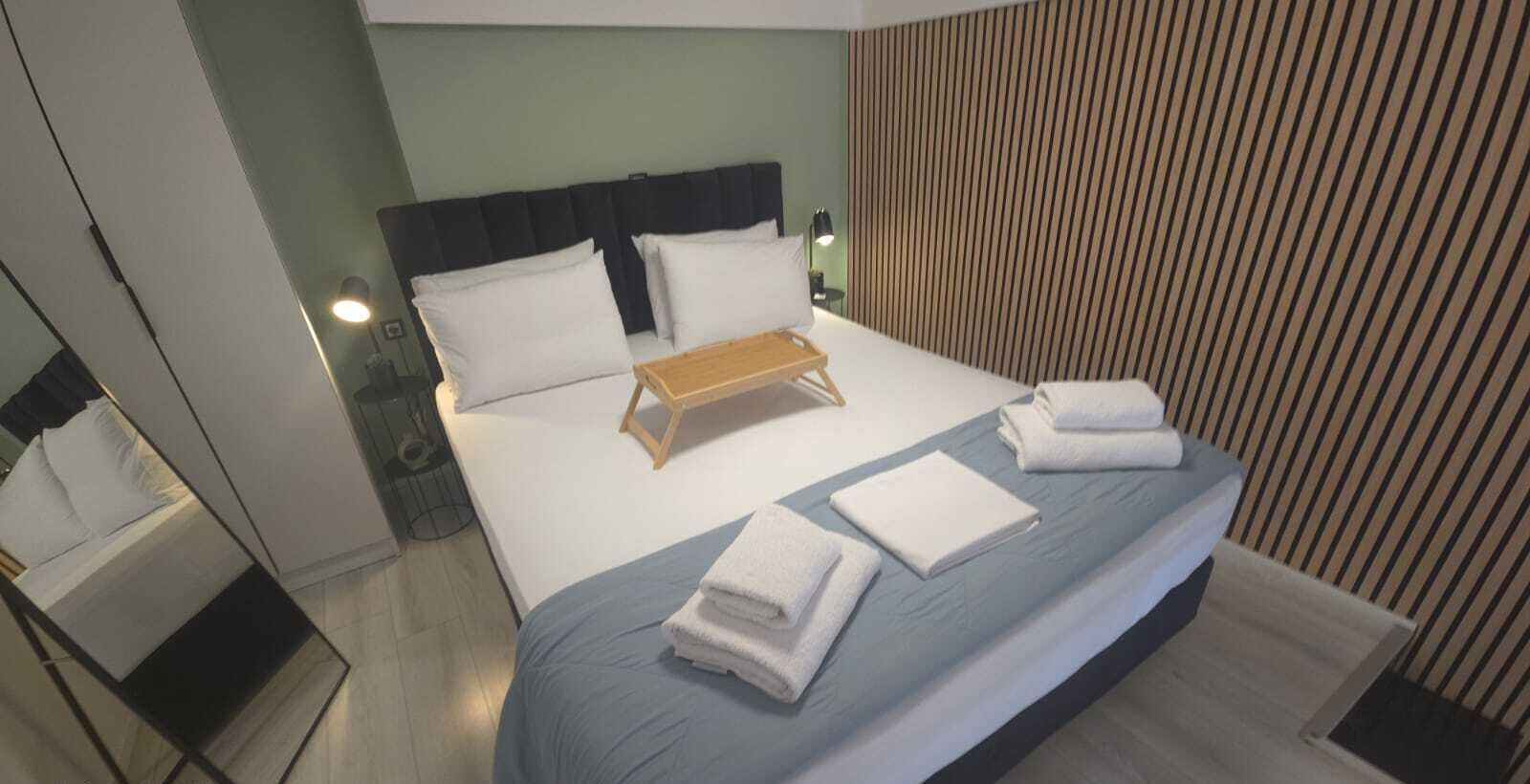 A hotel room with a bed, a bedside table, a lamp, and a striped wall.