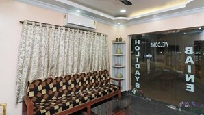 A reception area with a patterned sofa, a decorative shelf, and a glass door with "WELCOME" signage. - Baine Holiday Resort (Bolpur)