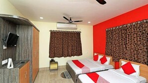 A hotel room with two beds, a TV, an air conditioner, and a ceiling fan. - Baine Holiday Resort (Bolpur)
