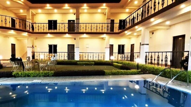 A multi-level pool area with a central pool, surrounded by seating and a well-lit interior. - Baine Holiday Resort (Bolpur)