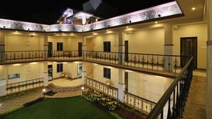 A multi-level hotel with a central courtyard, balconies, and a well-lit exterior. - Baine Holiday Resort (Bolpur)