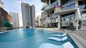 Un edificio moderno con piscina, diversi balconi e cielo sereno.