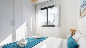 Ένα υπνοδωμάτιο με ένα κρεβάτι, ένα παράθυρο, ένα φωτιστικό και μια ντουλάπα.