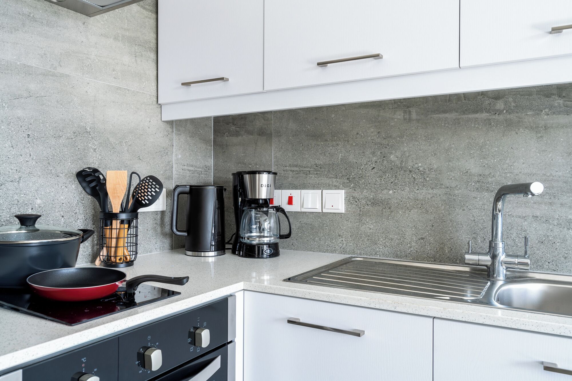 Et moderne køkken med gasblus, kaffemaskine og vask.