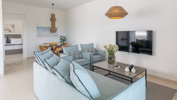 En moderne stue med en hjørnesofa, et sofabord og et fjernsyn ophængt på væggen.