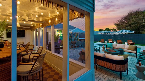 An outdoor dining area with wicker furniture and a poolside seating area. - PCB Stay w/ Heated Pool, Hot Tub, Bars, Game Room & Quick Walk to Beach (Panama City Beach)