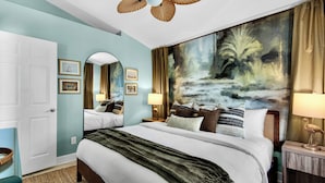 A hotel room with a large bed, a ceiling fan, a painting on the wall, and a nightstand with a lamp. - PCB Stay w/ Heated Pool, Hot Tub, Bars, Game Room & Quick Walk to Beach (Panama City Beach)