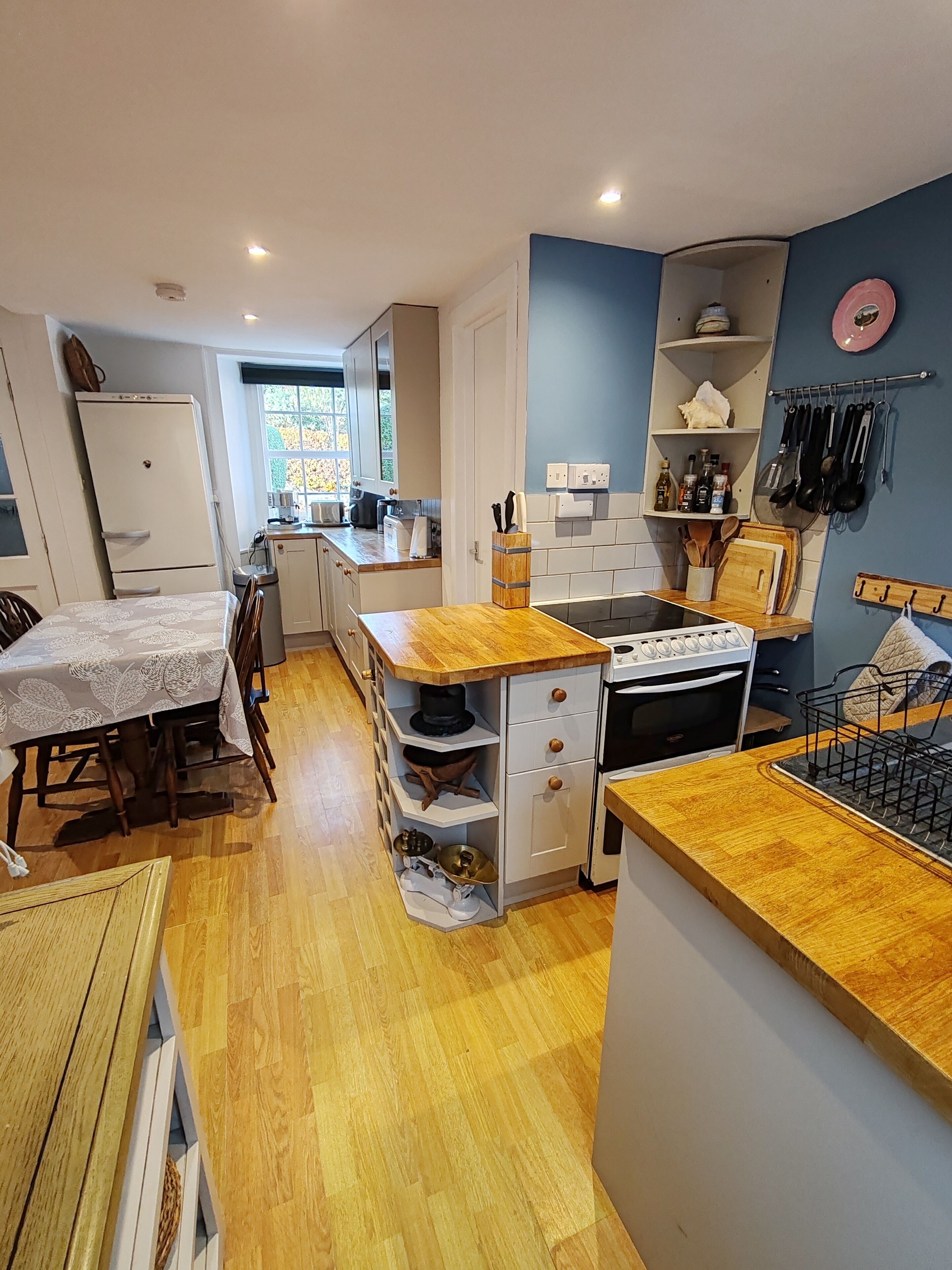 Une cuisine compacte dotée de plans de travail en bois, d’un four encastré et d’un coin repas avec une table et des chaises.