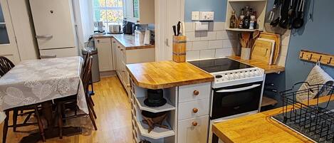 Une cuisine compacte dotée de plans de travail en bois, d’un four encastré et d’un coin repas avec une table et des chaises.