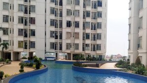 Ein modernes Apartmenthaus mit einem zentral gelegenen Schwimmbad, umgeben von einer angelegten Grünfläche.