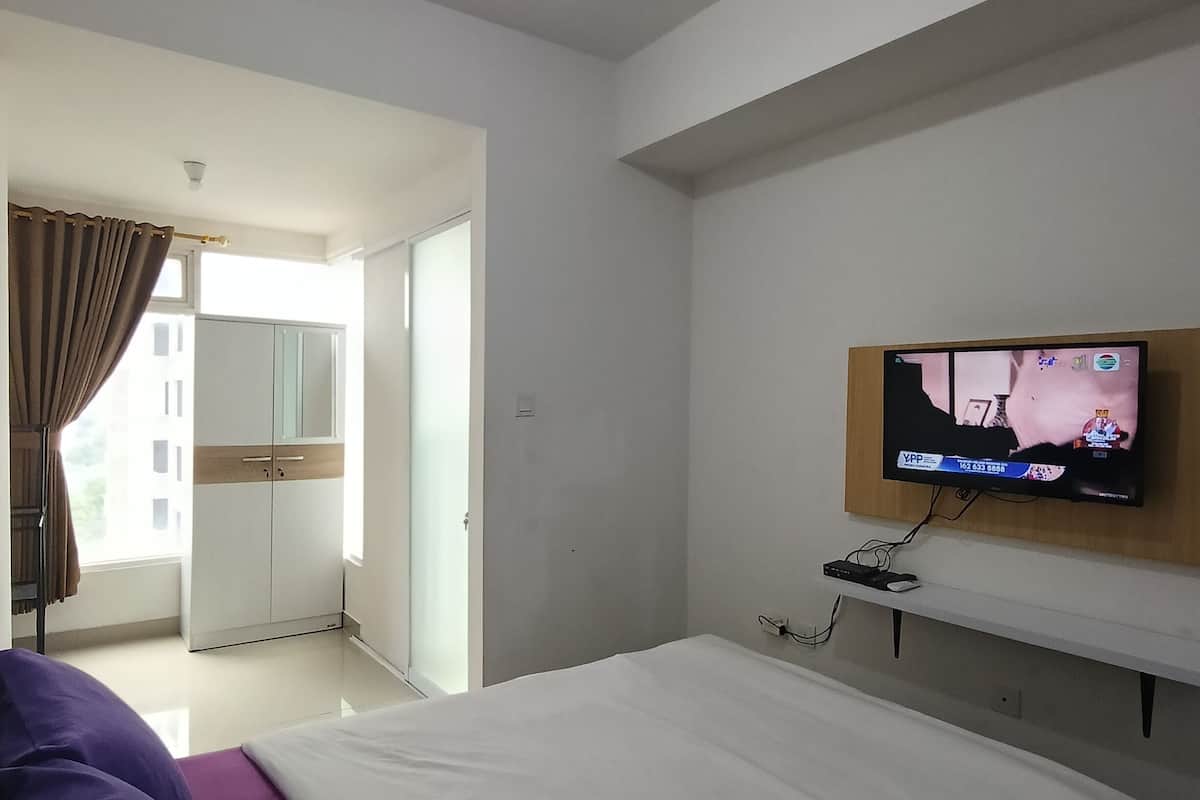 A hotel room with a bed, a television mounted on the wall, and a wardrobe.
