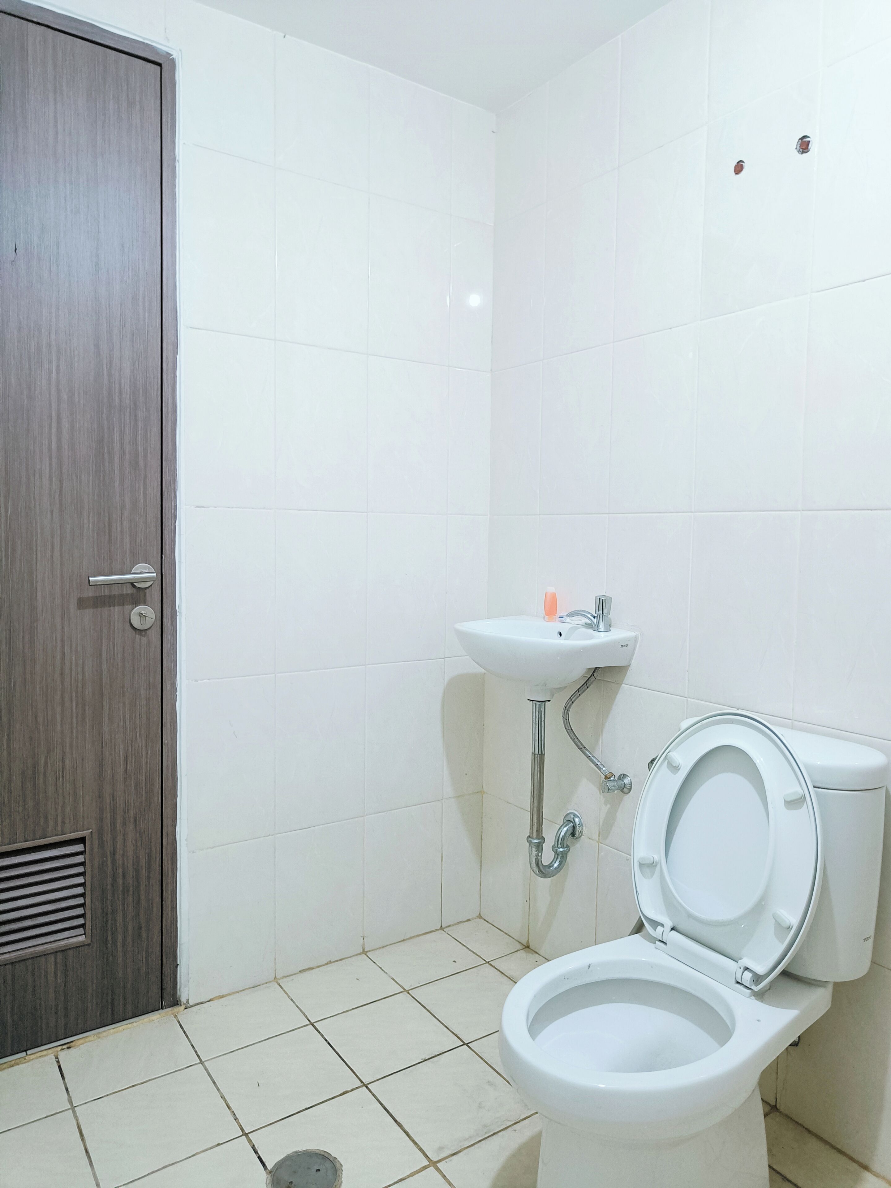 A small, clean bathroom with a toilet, sink, and a door.